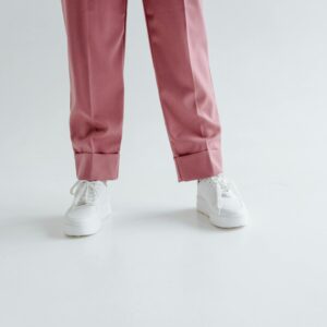 Close-up of pink pants and white sneakers in a studio setting with a white backdrop.